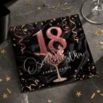 Polish 18th birthday invitation on a black, glittery card with a large pink 18 and a cartoon woman sitting on a cocktail glass amid gold confetti and ribbons